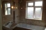 A full view of the bathroom showing the sink, shower screen, bath and fully integrated tiles